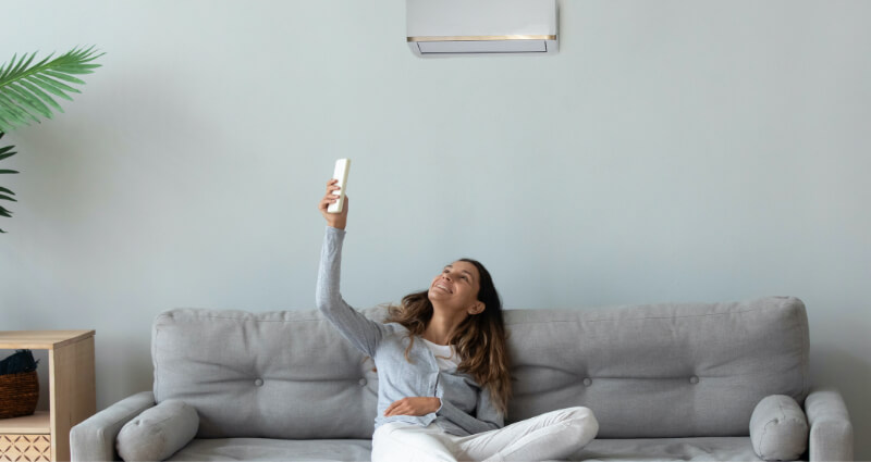 Woman sitting on couch under a minisplit.