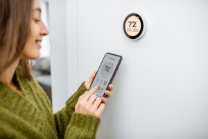 person-setting-thermostat-with-their-phone
