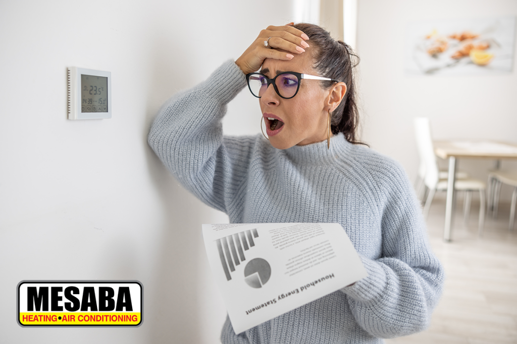 Woman cannot believe her own eyes the sum on her energy bill looking shocked at the thermostat on the wall next to her.
